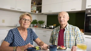 Senioren sitzen am Tisch in der Küche ihre Genossenschaftswohnung